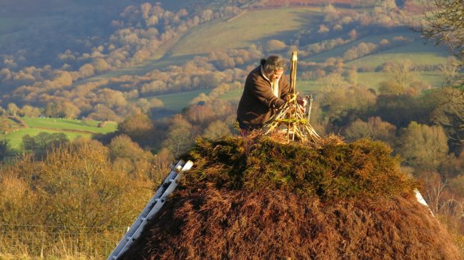 Kevin Blockley atop the roof of a neolithic style building at Out of Eden